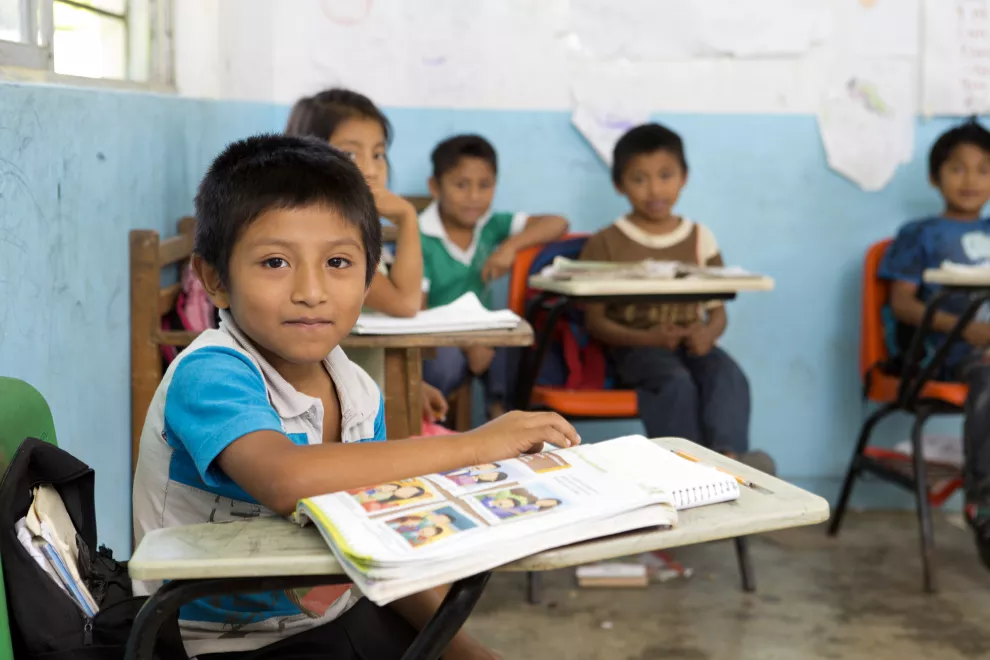 niños sentados en un salon de clases en sus pupitres