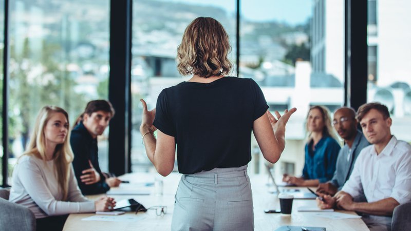 mujer hablando con su equipo dentro de una reunion empresarial