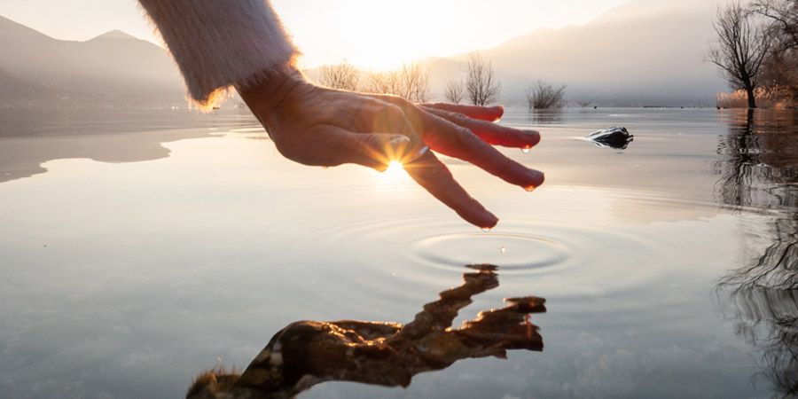 mano acercandose al agua para contemplar conscientemente el reflejo