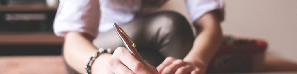 Mujer con un boligrafo escribiendo sus pensamientos en una hoja de papel