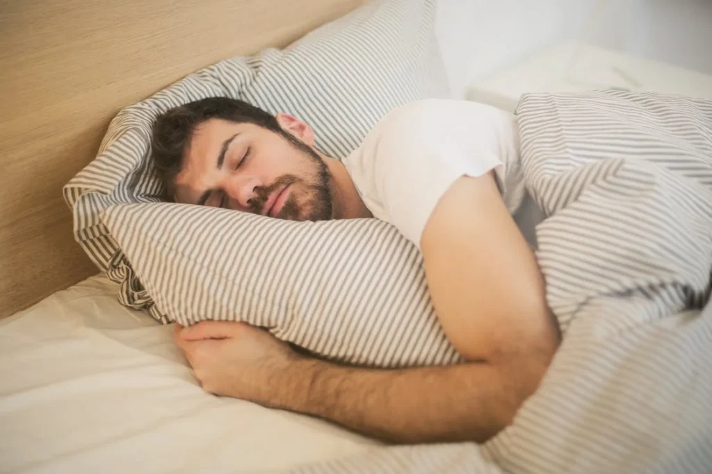 hombre durmiendo sobre su cama abrazando la almohada beneficio para la salud mental