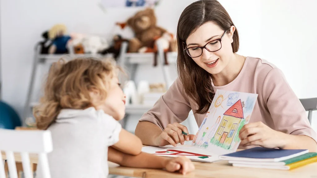 mujer enseñando a una niña un cuadro con una casa