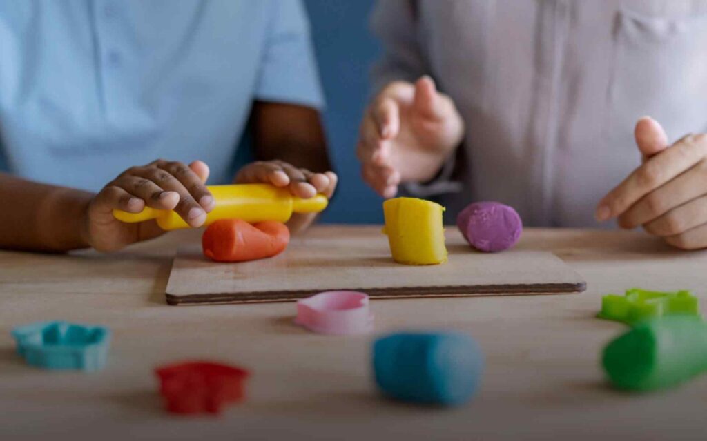 Dos niños jugando con plastilina en una mesa